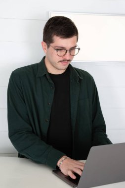 Bıyıklı, kahverengi saçlı, yakışıklı, iş adamı, beyaz arka planda ofis masasının önünde.