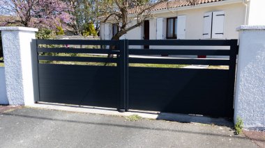 Banliyöde büyük, gri, koyu metalden, alüminyum, siyah kapı, bahçe kapısı.