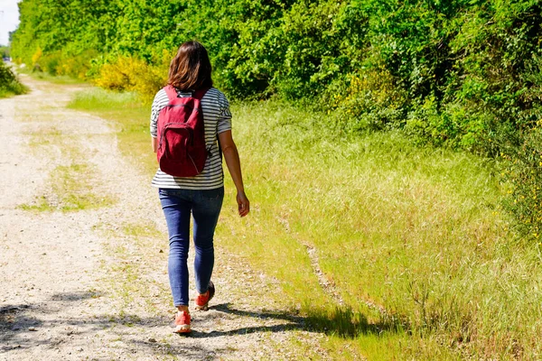 slim woman back rear view walking on forest trail country road park