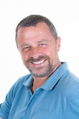 Beyaz arka planda duran, güler yüzlü, yakışıklı, orta yaşlı bir adamın portresi.