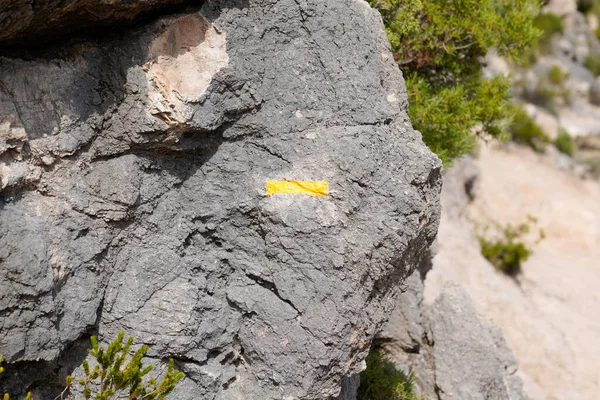 Hiking Trail path Marker on a stone with yellow signs drawn paint sign