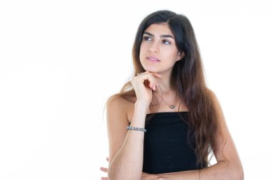 Düşünen genç bir kadın sol elini çenesine koyup boş beyaz arkaplanı kopyalıyor.