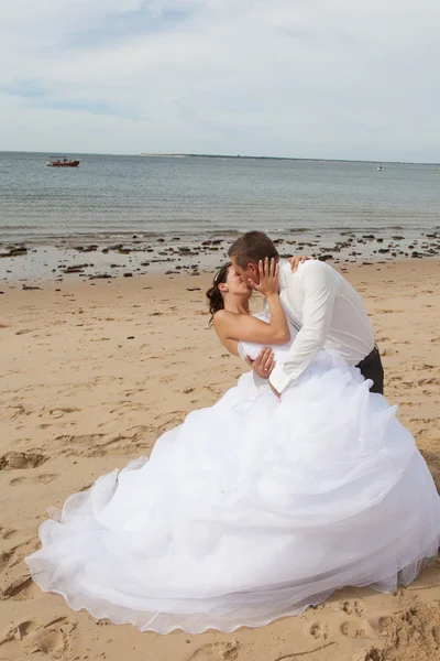 Brautpaar küsst sich am Strand — Stockfoto