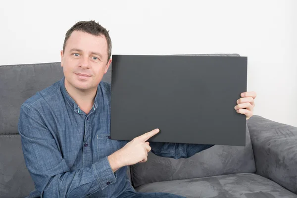 Sorrindo homem segurando um sinal preto em branco — Fotografia de Stock