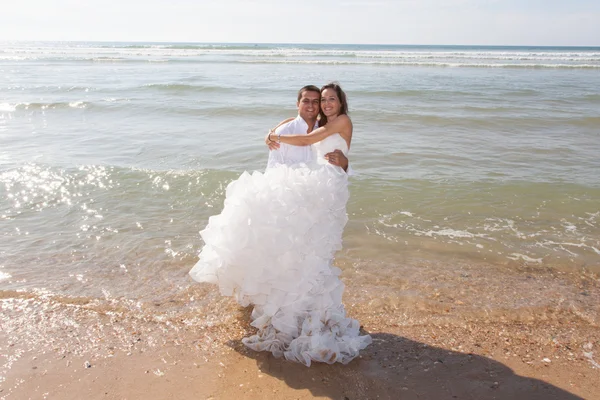 Mooie en mooi bruidspaar op het strand onder de blauwe hemel — Stockfoto