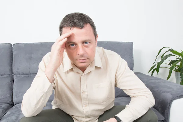 Portrait of a upset  man sitting on sofa — Stock Photo, Image