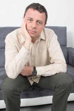 Evde koltukta oturan üzgün bir adam portresi