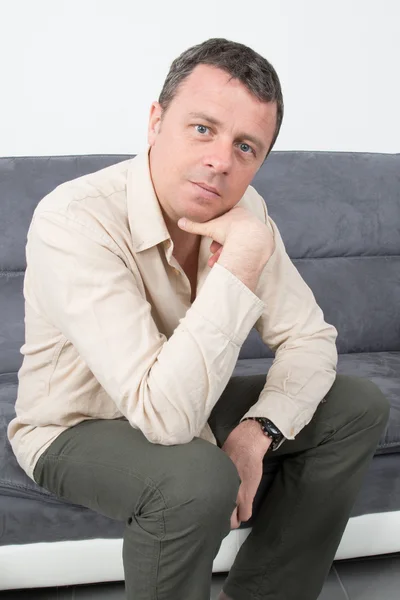 Portrait of a happy man sitting on couch in house — Stock Photo, Image