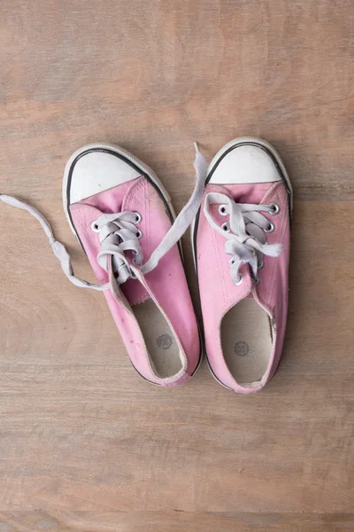 Крупный план розовых кроссовок, носимых подростком на деревянном фоне — стоковое фото