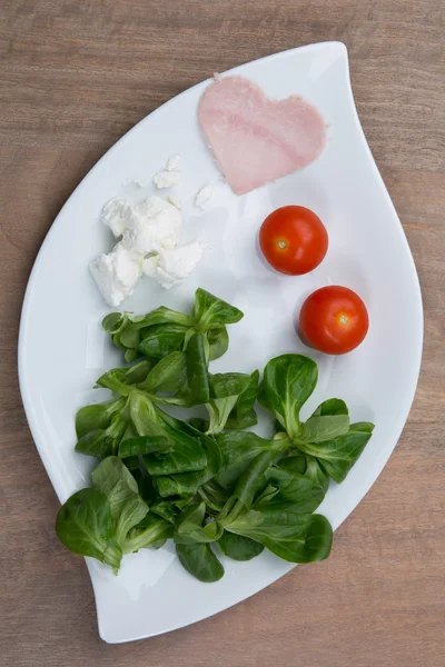 Salada de tomate e presunto em forma de coração na mesa de madeira — Fotografia de Stock