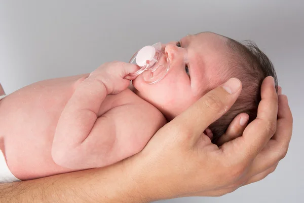 Recién nacido bebé es sostenido por su padre aislado en gris — Foto de Stock