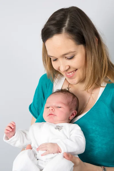 Portret van een gelukkige moeder met baby geïsoleerd op grijs — Stockfoto