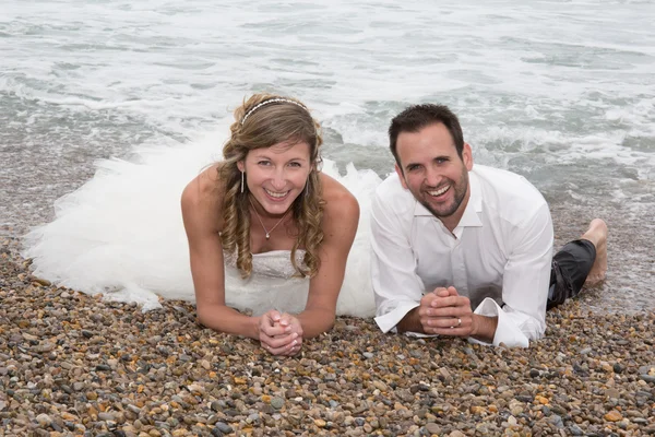 Pareja recién casada yaciendo en la playa — Foto de Stock