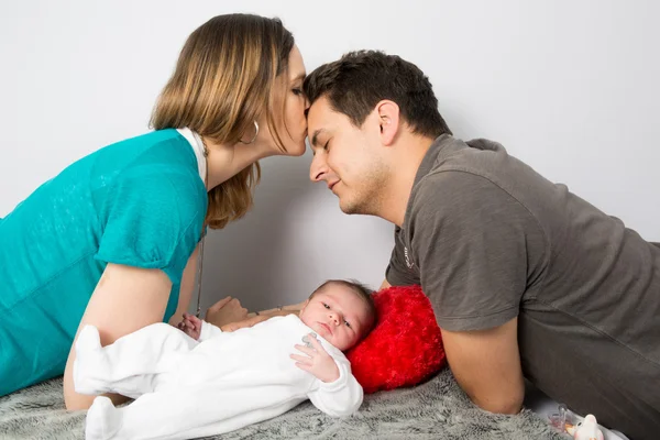 Stolze Eltern blicken auf ihre kleine Tochter und küssen sich — Stockfoto