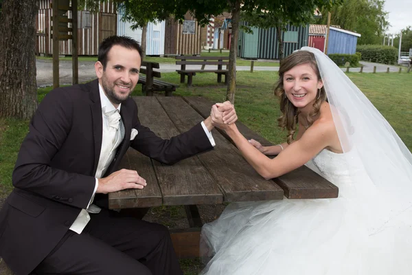 Junges glückliches frisch verheiratetes Paar kämpft im Armdrücken — Stockfoto