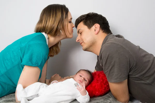 Stolze Eltern blicken auf ihre kleine Tochter und küssen sich — Stockfoto