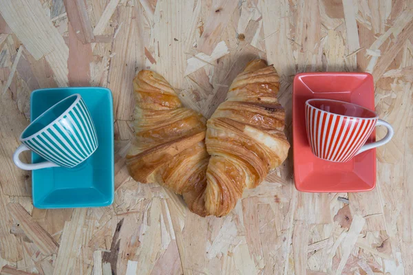 Dos croissants franceses frescos con taza de café sobre mesa de madera — Foto de Stock