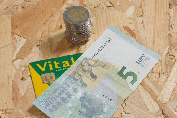 Concept van dure gezondheidszorg met munten, biljetten en Franse gezondheidskaart — Stockfoto
