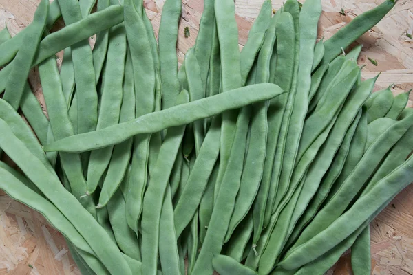 Frijoles verdes planos frescos sobre fondo de madera — Foto de Stock