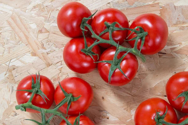 Tomates frescos em um grupo sobre a mesa de madeira — Fotografia de Stock