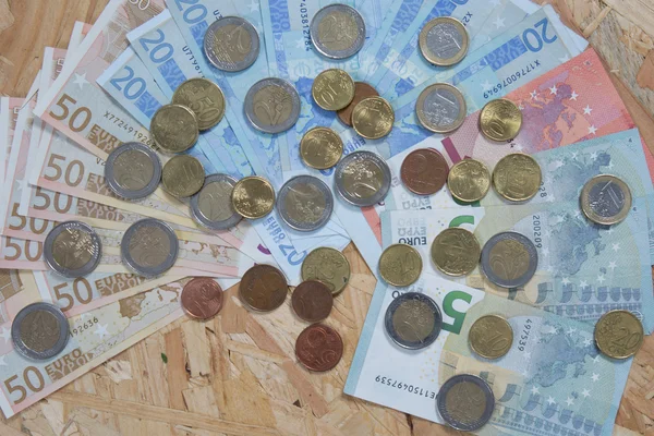 Bainha de notas e moedas de euro isoladas sobre fundo de madeira — Fotografia de Stock