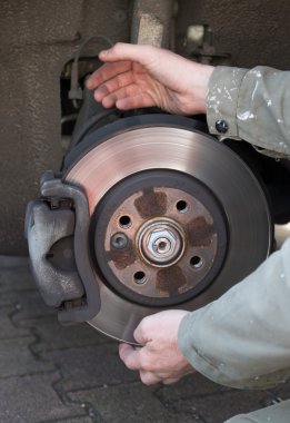 A mechanic is changing a wheel of a modern car clipart