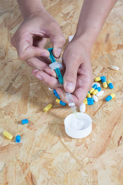 Drug syringe and cooked heroin on wooden table — Stock Photo, Image