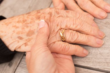 Young hand holds hands of an elderly person
