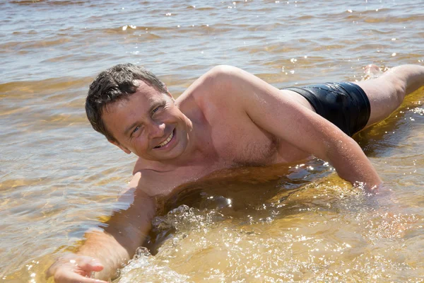 Man in het water aan het strand blij te zijn in vakantie — Stockfoto
