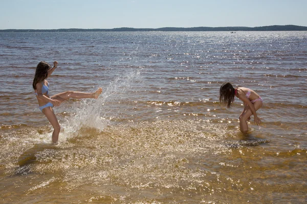Två flickor, ha roligt tillsammans på stranden i vattnet — Stockfoto