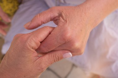 Daha genç bir kadının elini tutarak yaşlı bir kadın elinde.