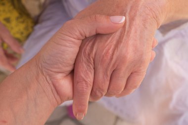 Hands of a woman holding the hand of a younger woman.