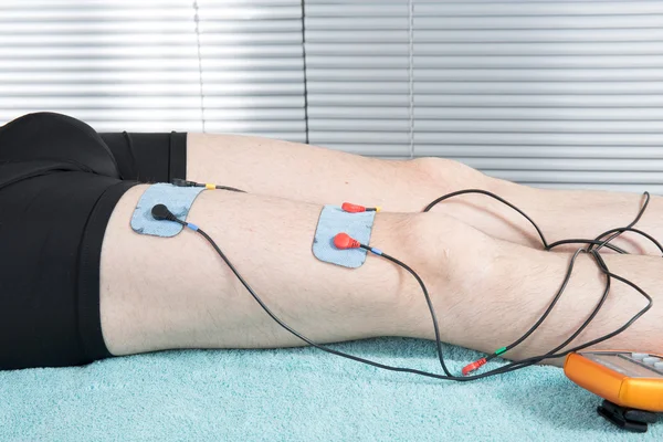 Electrical muscle stimulation in physical therapy. Therapist positioning  electrodes on a patient's knee Stock Photo - Alamy