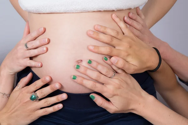 Kvinnans händer på gravid kvinna mage. inomhus skott — Stockfoto