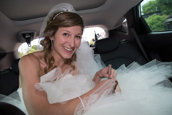Красивая невеста в машине с свадебным платьем — стоковое фото