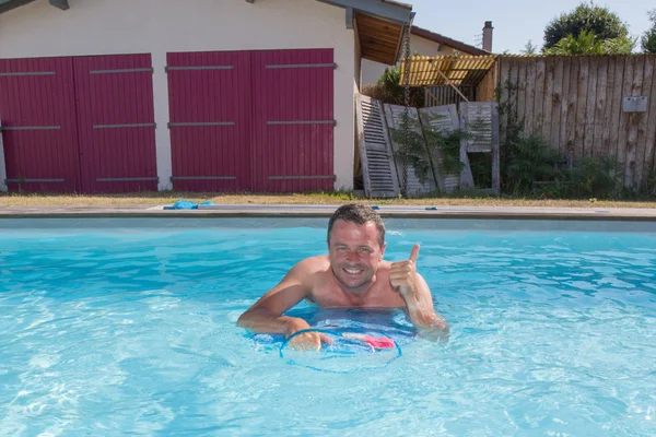 Uomo nuotare con la tavola da surf in acqua blu nuotare e sorridere — Foto Stock