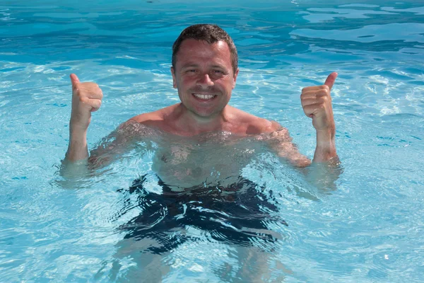 Uomo nuotare con la tavola da surf in acqua blu nuotare e sorridere — Foto Stock