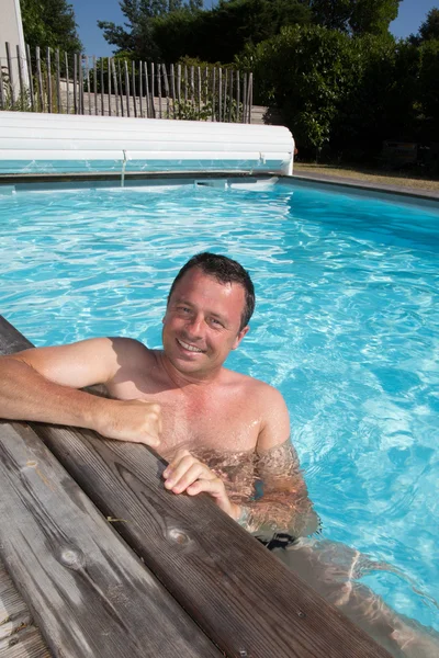 Felice uomo attraente appoggiato al bordo della piscina — Foto Stock