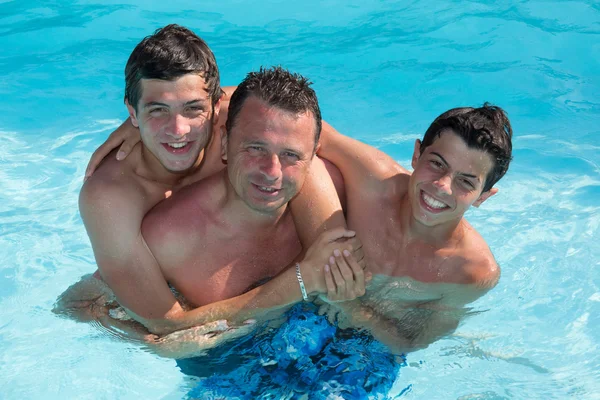 Buon padre con i suoi due figli divertirsi in piscina — Foto Stock