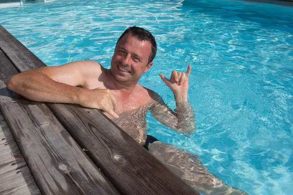 Gelukkig aantrekkelijke man leunend op de rand van het zwembad — Stockfoto