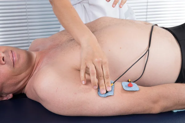 Hombre recibiendo un masaje eléctrico en su brazo — Foto de Stock