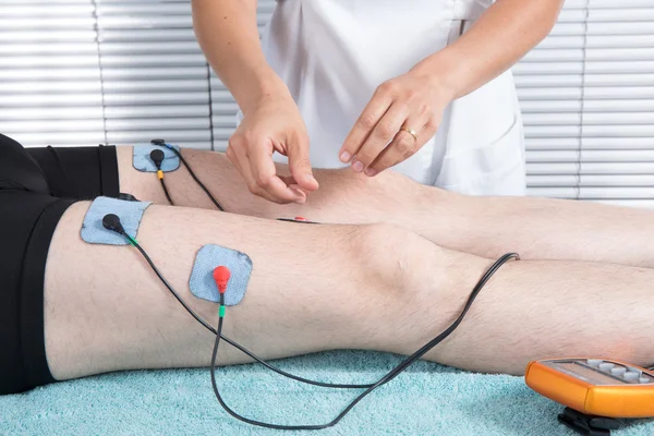 Man getting electric massage for leg muscles in spa — Stock Photo, Image