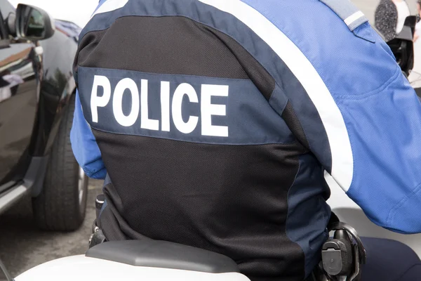 Prise de vue du dos d'une veste d'agent de police avec le mot police écrit au dos — Photo