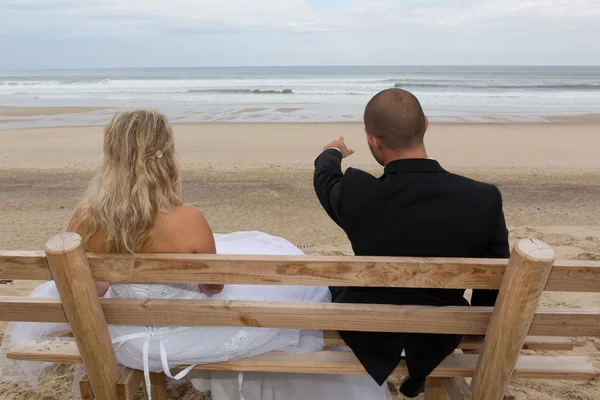 海の前にあるベンチで結婚式のカップル — ストック写真