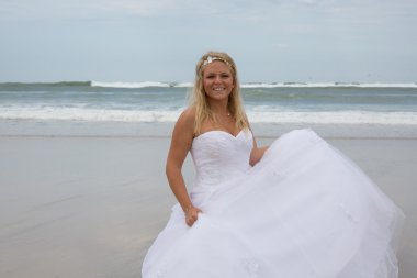 Sahilde düğün elbisesiyle sarışın bir kadın