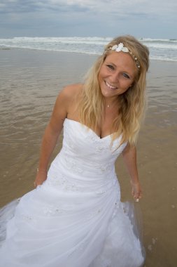 Sahilde düğün elbisesiyle sarışın bir kadın
