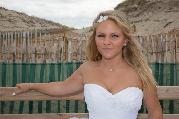 Una mujer rubia en su vestido de novia en la playa — Foto de Stock