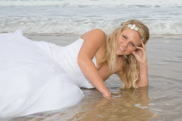 Une femme blonde dans sa robe de mariée à la plage — Photo