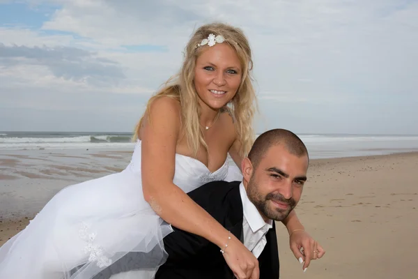 Casal apaixonado piggyback jogando em uma praia no oceano azul — Fotografia de Stock