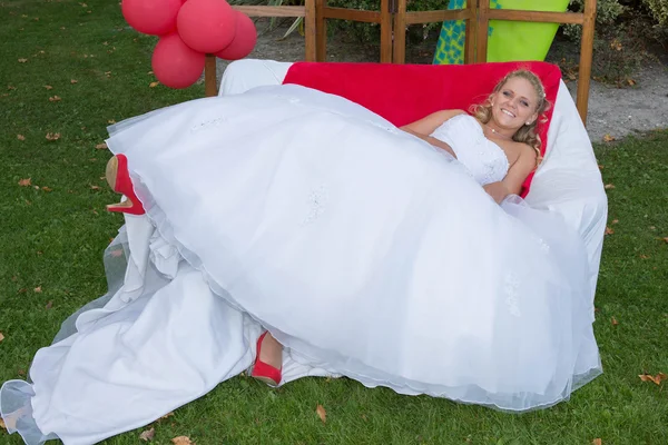 Сумасшедшая блондинка на красном диване счастлива — стоковое фото